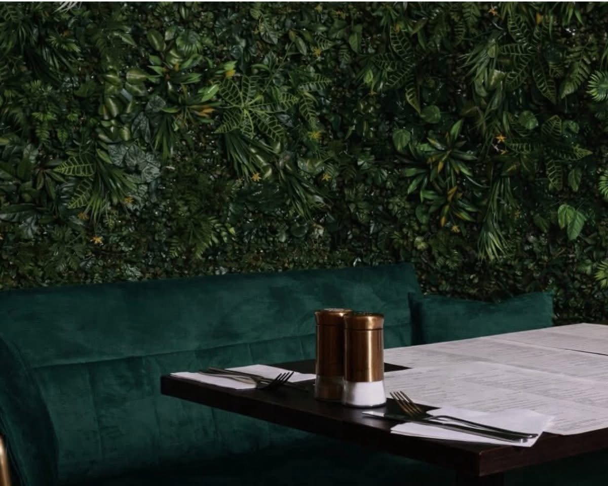 The green velvet booth by the plant wall