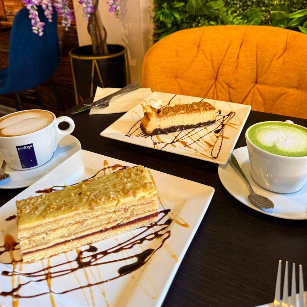 Cake and coffee at a table by the green wall