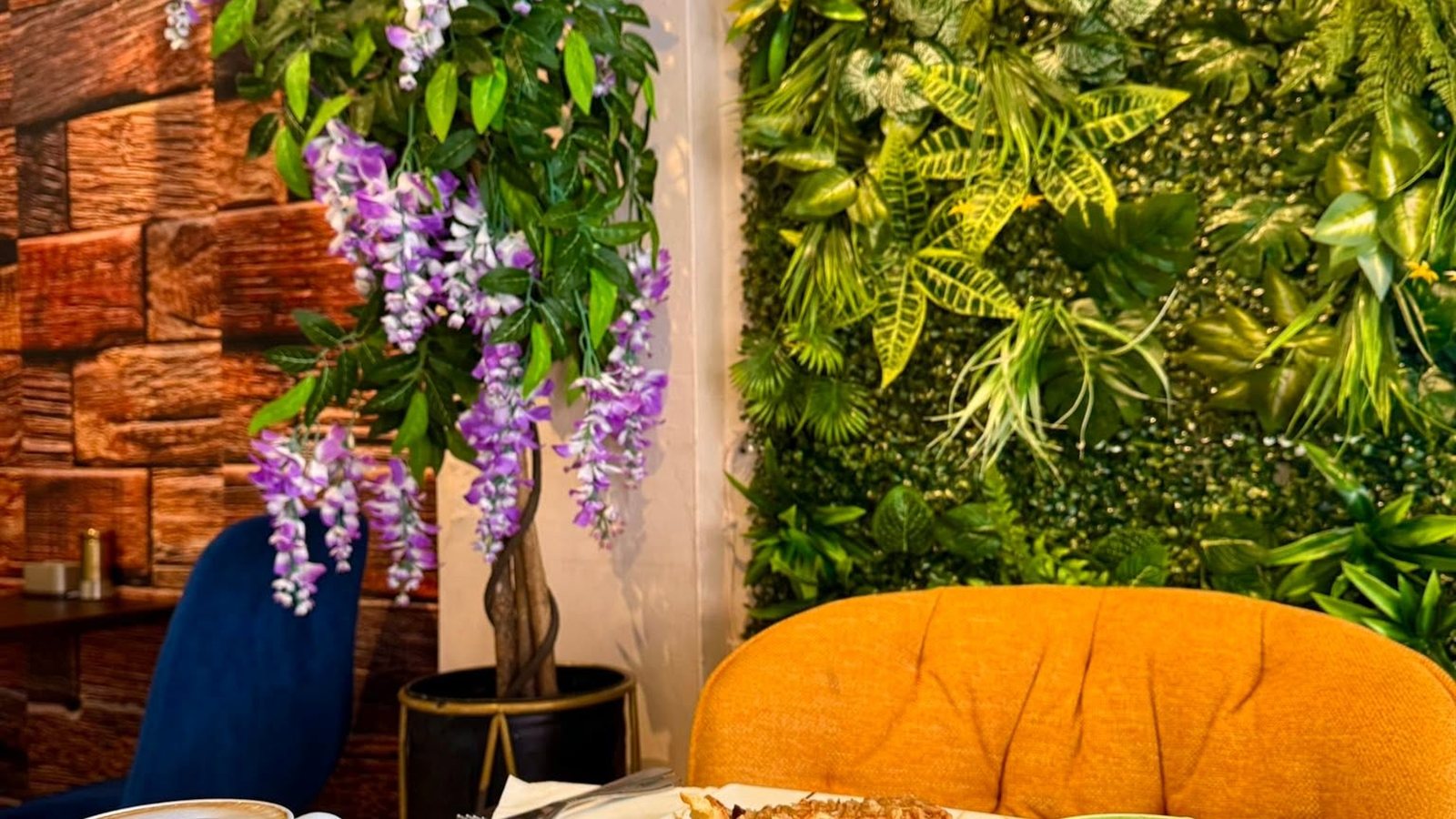 Inside The Coffee Tree, with the green wall, wisteria and a table set with coffee and cake